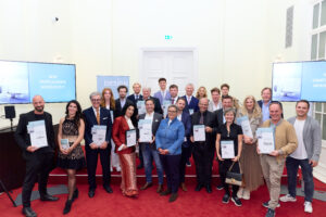 Im Bild v.l.n.r. vorne, vor der Bühne stehend: Josef Deisl (Deisl Sauna & Wellness – Gewinner Bad & Wellness), Chiara Reichel, Christian Reichel und Dagmar Reichel (Designflagship by Eybl – Sonderpreis Familienunternehmen), Martin Aigner (Lichtprojekt – Gewinner Licht & Leuchten), Anna M. Del Medico (Autorin), Matthias Maringer (Lichtprojekt – Gewinner Licht & Leuchten), Thomas Chuchlik (HeimkinoWelt – Sonderpreis Home Cinema Experience), Michael Stein (Herausgeber/Verleger medianet), Anita Auinger (Auinger Ideenreich für schönes Wohnen – Gewinner Möbel und Design), Andrea Popinger-Schwab (Wohnstudio Schwab – Gewinner Raumausstattung), Hans und Johannes Auinger (Auinger Ideenreich für schönes Wohnen – Gewinner Möbel und Design) Hinten auf der Bühne stehend: Katharina Kollarits und Matthias Kainz (Kramer & Kramer – Gewinner Outdoor), Konstantin Busse (Hästens Wien – Art of Sleep – Gewinner Schlafen), Wolfgang Faulmann (Faulmann & Faulmann – Sonderpreis Lebenswerk), Karl Josef Schauer (See+Maschik I SieMatic by Wohnwelt Maier – Gewinner Küche), Christian Chladek (Allsound – Gewinner Multimedia), Karl Schauer und Karla Lilli Schauer (See+Maschik I SieMatic by Wohnwelt Maier – Gewinner Küche), Alfred Maierhofer (Wohndesign Maierhofer – Sonderpreis Wohnkonzepte), Fabian Haas (See+Maschik I SieMatic by Wohnwelt Maier – Gewinner Küche), und auf der Bühne ganz rechts neben dem Bildschirm Ralf Busse (Hästens Wien – Art of Sleep – Gewinner Schlafen)